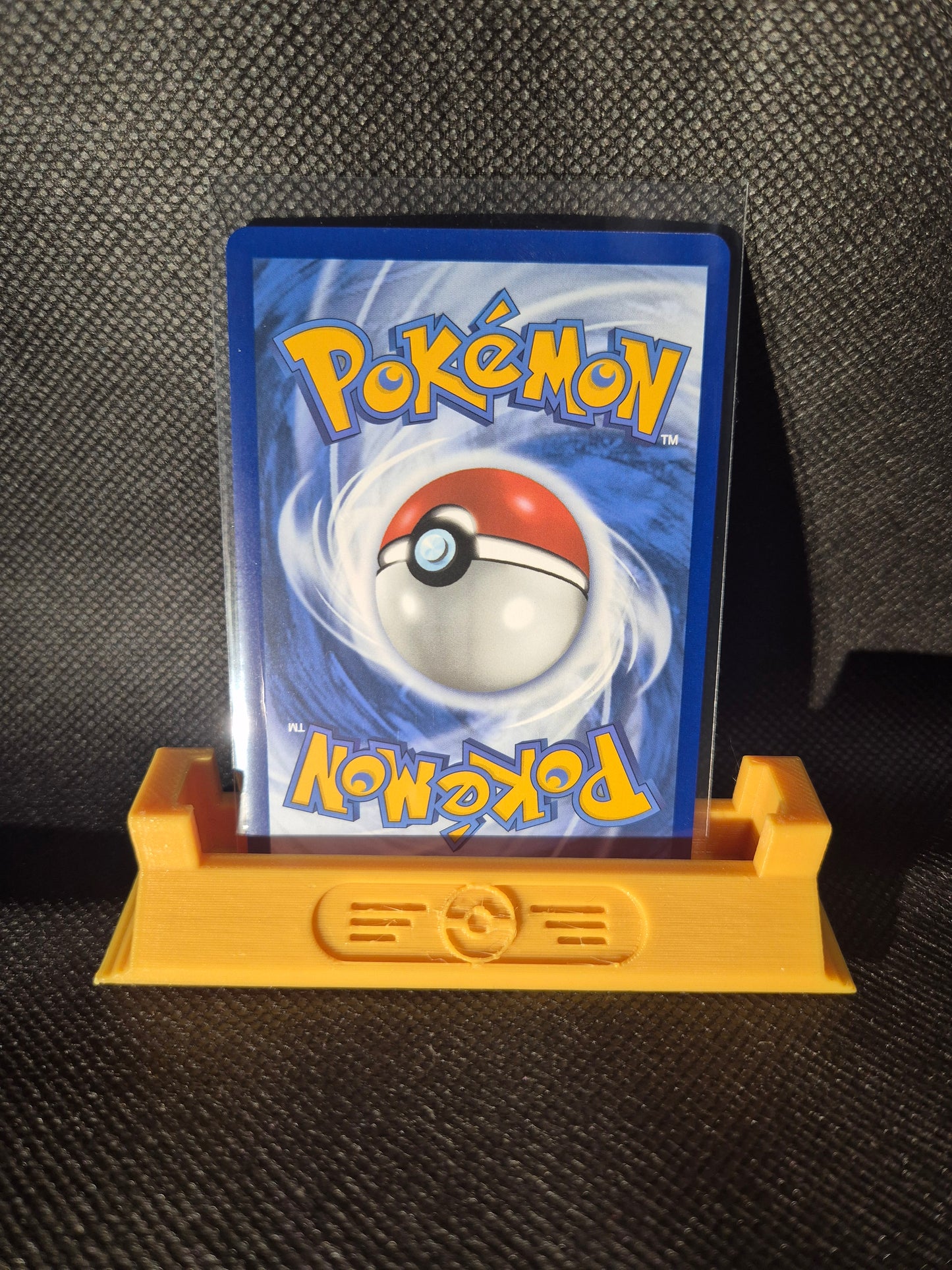 Pokémon trading card with a yellow holder on a textured surface