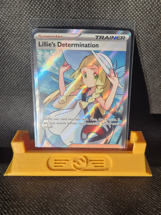 Trading card featuring a character with a hat and rainbow elements, held by a yellow card holder on a textured black surface.